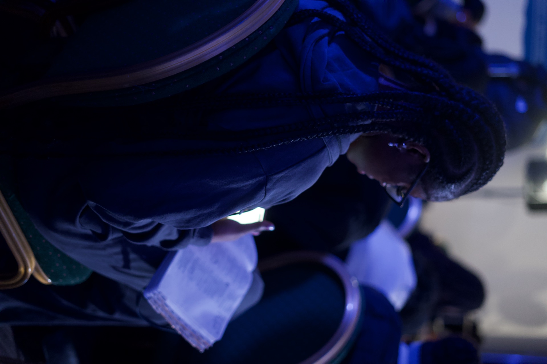 A woman reading her Bible by phone light during service